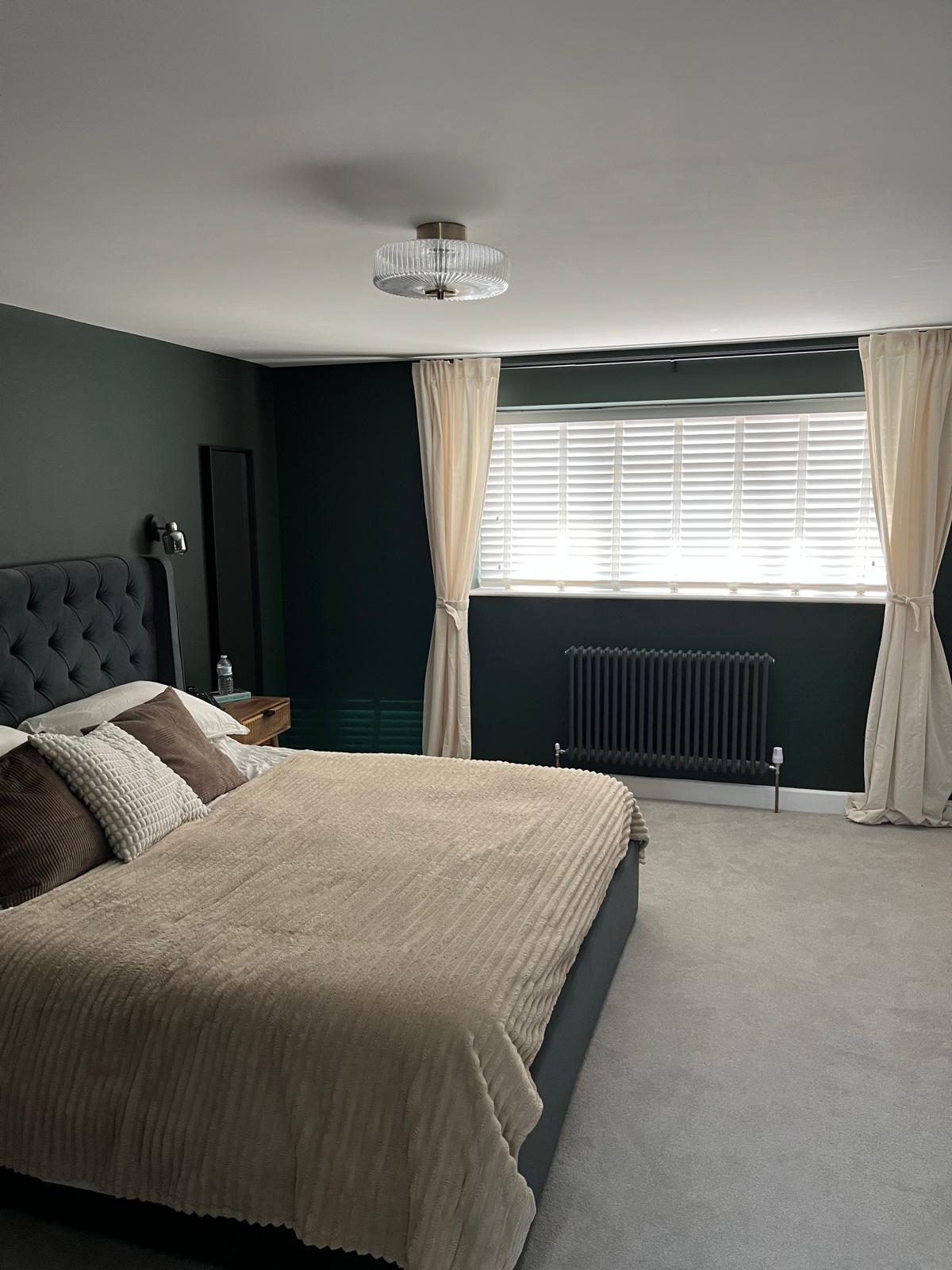 Green bedroom with cream curtains